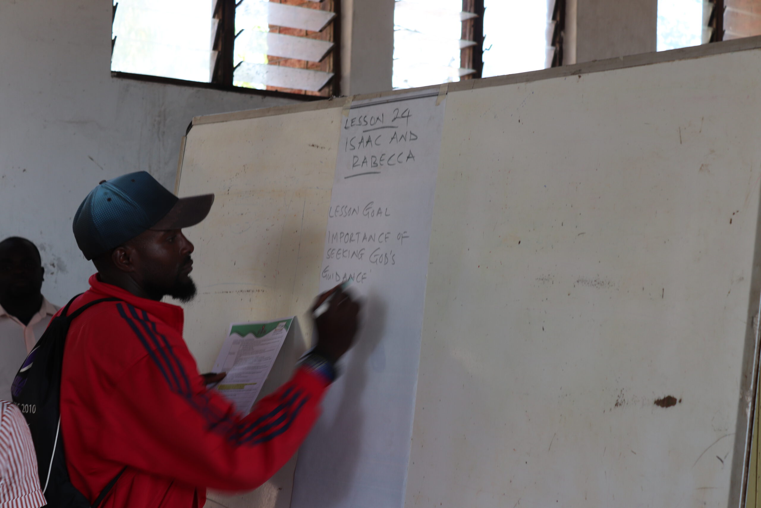 Man in Malawi schrijft op een whiteboard.