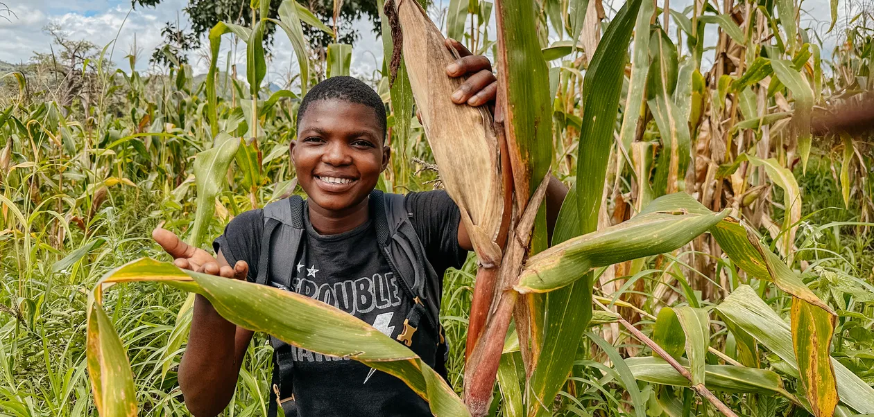 Vrouw in maisveld in Malawi Medewerker is blij met de maisoogst