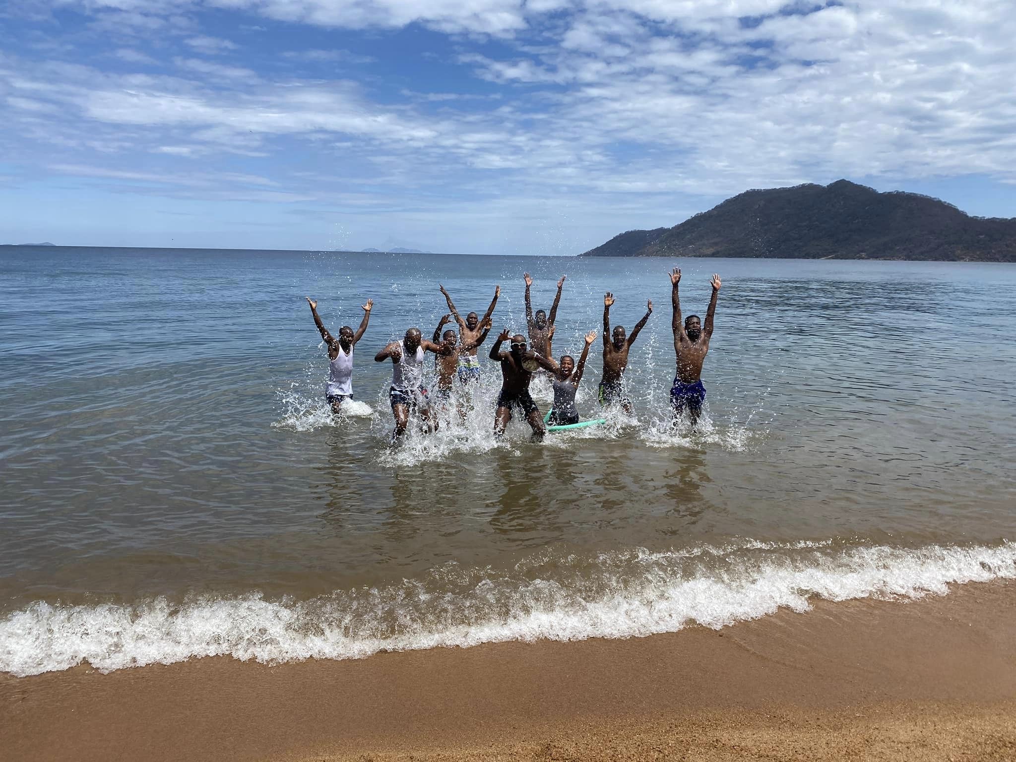 Management team poseert voor groepsfoto bij Lake Malawi Lake Malawi groepsfoto